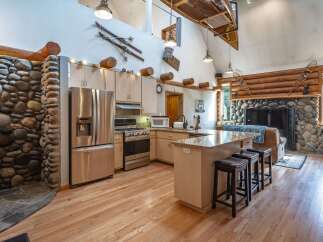 Experience rustic charm in this spacious kitchen featuring a large stone fireplace and a cozy living area.