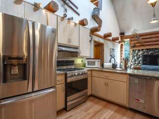 Experience rustic charm in this mountain kitchen, featuring a spacious stainless steel refrigerator and a professional-grade gas range.