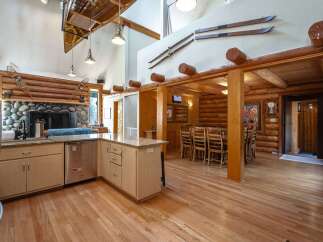 Experience rustic charm in this spacious log home featuring a grand stone fireplace and a soaring vaulted ceiling adorned with a canoe.