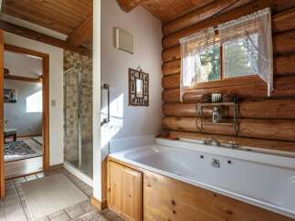 Experience rustic charm in this log cabin bathroom, featuring a luxurious jetted tub perfect for unwinding.