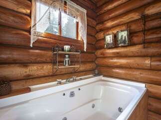 Experience rustic charm in this log cabin bathroom, featuring a luxurious jetted tub perfect for relaxation.