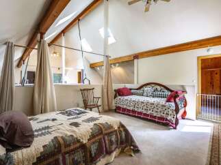 Discover this charming attic bedroom featuring a cozy quilt-covered bed and a rustic daybed, perfect for guests or family.
