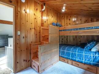 This charming bedroom features a space-saving bunk bed with built-in storage drawers, perfect for maximizing room in a cabin or vacation home.