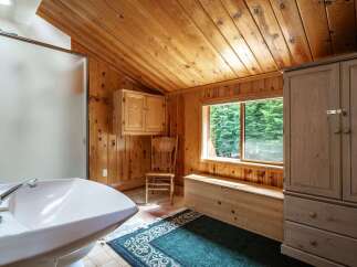 Experience rustic charm in this bathroom featuring warm wood paneling and a vaulted ceiling.