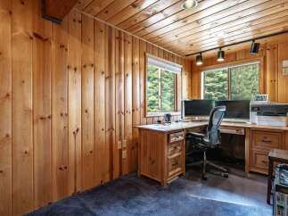 This cozy home office features warm wood paneling on the walls and ceiling, creating a rustic and inviting atmosphere.