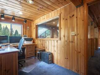This cozy home office features warm wood-paneled walls and a ceiling, creating a rustic and inviting atmosphere.