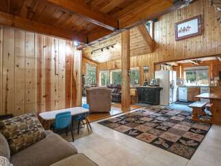 Experience rustic charm in this spacious living area, featuring warm wood paneling and exposed beams that create a cozy, cabin-like atmosphere.