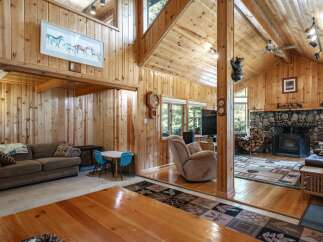 Experience rustic charm in this spacious living area, featuring a grand stone fireplace and a cozy wood-burning stove perfect for chilly evenings.