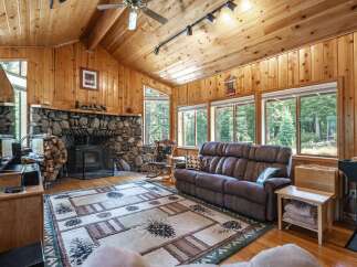 Experience rustic charm in this cozy living room featuring a magnificent stone fireplace and a wood-burning stove, perfect for chilly evenings.