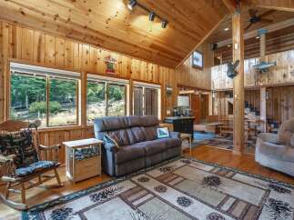 Experience rustic charm in this spacious living area featuring a cozy recliner sofa and a traditional rocking chair, perfect for relaxing after a day outdoors.