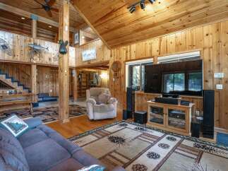 Experience rustic charm in this spacious living area featuring a soaring wood-paneled ceiling and a cozy fireplace.