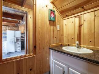 Step into this charming cabin bathroom featuring a rustic wood-paneled interior and a convenient vanity with a granite countertop.