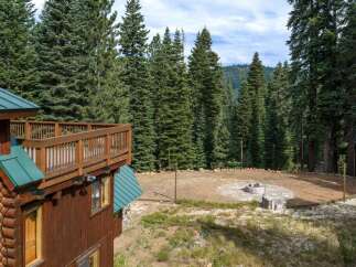 Experience the ultimate mountain retreat with this stunning log home, featuring a spacious wooden deck perfect for enjoying the serene forest views.