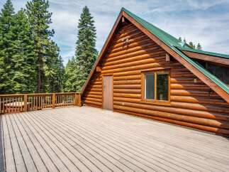 Experience rustic charm in this stunning log cabin, featuring a spacious wooden deck perfect for outdoor entertaining and enjoying the surrounding forest views.