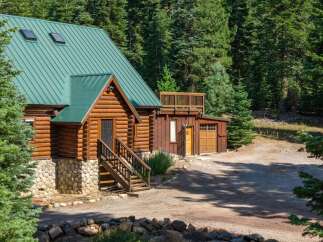 Nestled amidst a dense forest, this charming log cabin offers a rustic retreat with its natural wood exterior and a durable green metal roof.