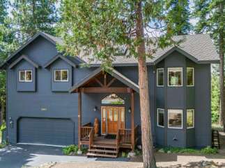 Discover this stunning dark blue home nestled among tall pine trees, offering a serene and private retreat.