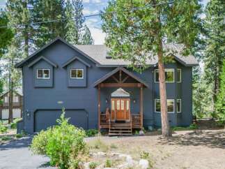 Discover this stunning dark blue home nestled amongst tall pine trees, offering a serene and private retreat.