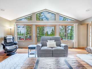 Experience breathtaking mountain views from this stunning living room, featuring a wall of windows and a unique triangular skylight that floods the space with natural light.
