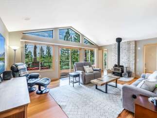 Experience breathtaking mountain and forest views from this stunning living room, featuring a dramatic vaulted ceiling with expansive triangular windows.