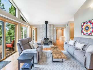 Experience breathtaking natural beauty from this stunning living room, featuring expansive windows that frame lush forest views.