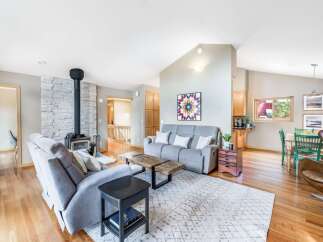 Experience comfortable living in this spacious open-concept home, featuring a striking stone-clad fireplace and a modern wood-burning stove.