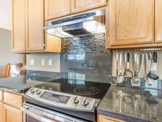 This kitchen features elegant light wood cabinetry and a sleek stainless steel range hood.
