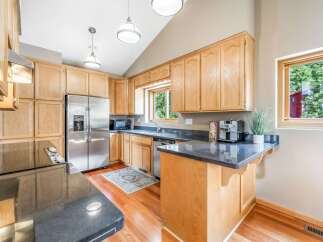 This spacious kitchen boasts beautiful light wood cabinetry and sleek granite countertops, offering ample storage and workspace.