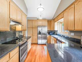 This spacious kitchen boasts beautiful light oak cabinetry, offering ample storage and a warm, inviting aesthetic.
