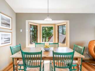 Enjoy meals with a view in this charming dining area, featuring a bay window that floods the space with natural light and offers picturesque forest scenery.