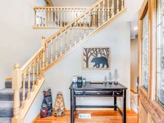 Welcome guests into this charming entryway featuring a beautiful wooden staircase with intricate railings.