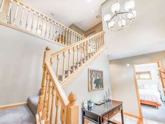 Step into this charming home featuring a beautiful wooden staircase with plush carpeted steps, perfect for welcoming guests.