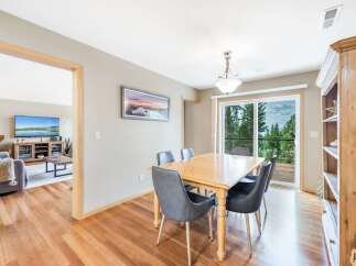 Enjoy meals with a view in this charming dining area, featuring a light wood table and sleek grey chairs.
