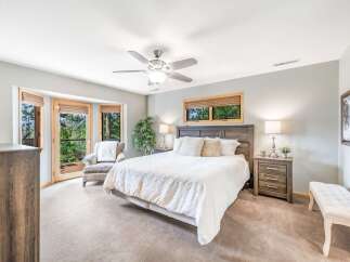 Experience serene living in this inviting bedroom, featuring a plush king-sized bed and a cozy armchair by the bay windows.