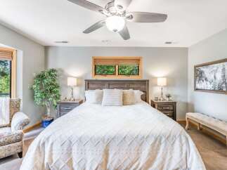 Experience ultimate comfort in this beautifully appointed bedroom, featuring a plush king-sized bed adorned with crisp white linens and decorative pillows.