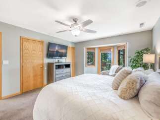 Experience ultimate comfort in this spacious bedroom, featuring a plush king-sized bed adorned with luxurious bedding and decorative pillows.