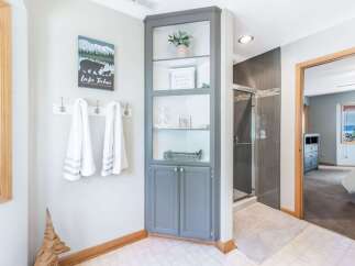 This bathroom features a tall, grey built-in cabinet with open shelving and lower cabinets, perfect for storing toiletries and displaying decor.