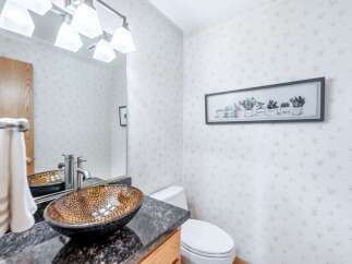 This charming bathroom features a stylish vessel sink atop a granite countertop, complemented by a modern faucet and a decorative mirror.