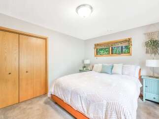 This charming bedroom features a comfortable queen-size bed with a stylish geometric-patterned duvet and plush pillows.