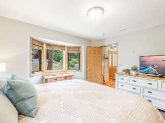 Experience serene living in this charming bedroom, featuring a large bay window that floods the space with natural light and offers picturesque views of the surrounding greenery.