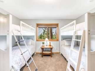 This charming bedroom features two sets of white bunk beds, perfect for accommodating multiple guests.