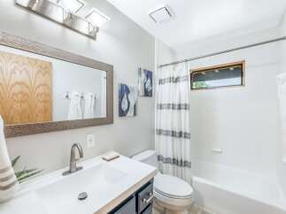 This modern bathroom features a sleek vanity with a large framed mirror, complemented by contemporary light fixtures.