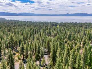 Nestled within a dense forest, this property offers a serene escape with stunning lake views in the distance.
