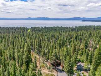 Nestled amidst a dense forest, this property offers a serene escape with stunning lake and mountain views in the distance.