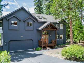 Discover this stunning dark blue home nestled amongst tall pine trees, offering a serene and private mountain retreat.
