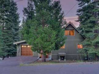 Nestled amongst tall pine trees, this charming home offers a serene retreat.
