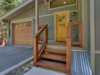 Charming mountain home featuring a warm wooden garage door and a vibrant yellow front door, inviting you into a cozy retreat.
