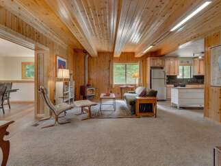 Experience cozy living in this charming cabin-style home featuring warm wood paneling throughout and a rustic wood-burning stove.