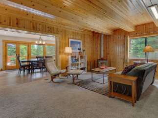Experience cozy living in this charming cabin-style home, featuring warm wood paneling throughout and a welcoming living area centered around a wood-burning stove.