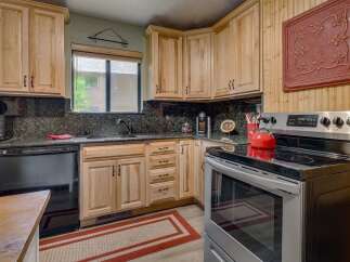 This charming kitchen features light wood cabinetry complemented by dark granite countertops and a matching backsplash.