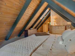 Experience rustic charm in this A-frame bedroom, featuring warm wood paneling and exposed beams.